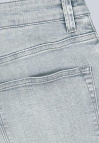 Light blue denim jeans with a smooth texture, featuring two back pockets and visible stitching along the seams and pocket edges.