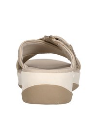 Beige sandaalit, joissa on takastrappi, litteat valkoiset pohjat, teksturoitu beige sisäpohja, koristeellista tikkausta remmissä ja minimalistinen muotoilu.