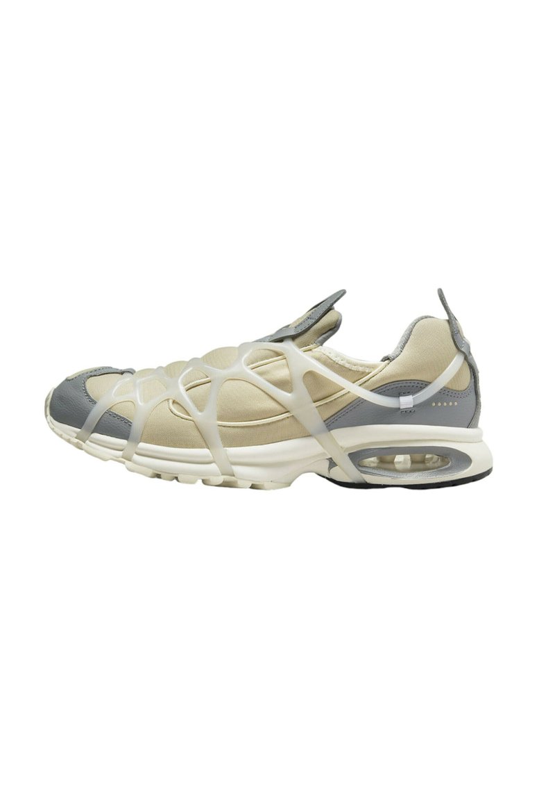 Sneakers with a beige and gray mesh upper, featuring a unique white rubber overlay design. Rounded toe and visible air cushioning in sole.