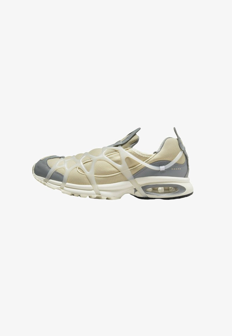 Sneakers with a beige and gray mesh upper, featuring a unique white rubber overlay design. Rounded toe and visible air cushioning in sole.