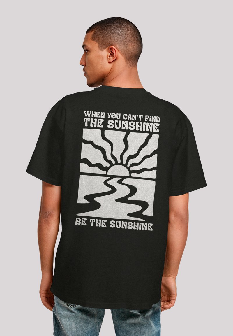 Schwarzes Baumwoll-T-Shirt mit einem grafischen Druck auf der Rückseite, der eine Sonne und ein gewelltes Flussdesign zeigt, begleitet von weißem Text.