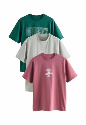 Trois t-shirts à manches courtes : un vert avec un motif graphique, un gris clair avec un motif graphique blanc, et un rose avec un design d'arbre blanc. Tous sont en coton et de coupe décontractée.