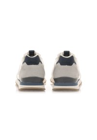 Zapatillas deportivas para hombres que presentan una combinación de ante gris claro y acentos en azul marino, con una suela de goma texturizada y una lengüeta en el talón para facilitar su uso.
