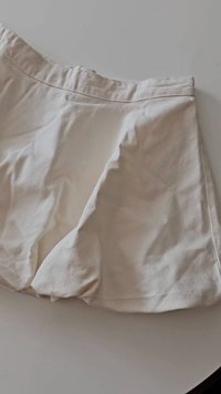 Jupe en coton beige clair, dotée d'une coupe évasée avec une texture lisse et des plis subtils, agrémentée d'une taille simple.