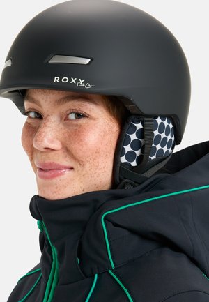 Czarny kask narciarski z logo ROXY, matowe wykończenie, srebrne akcenty. Wyłożony podszewką w kropki, w połączeniu z czarną kurtką z zielonymi wykończeniami.