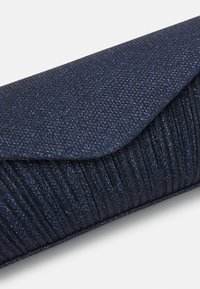 Pochette bleue marine pailletée avec un design plissé texturé et une fermeture à rabat plié, sur fond blanc.