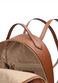 Sac à dos en cuir marron avec une finition texturée, une fermeture éclair dorée et un compartiment intérieur comprenant une poche zippée et une doublure en tissu.