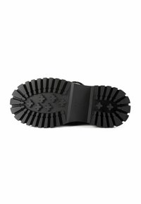 Suela de goma negra con profundos surcos y prominentes tacos. El diseño presenta una superficie lisa con una cresta central y un detalle de marca.