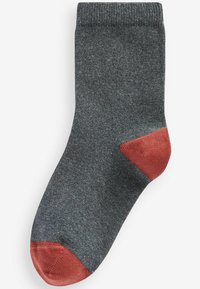 Chaussette grise en matériau doux, avec un talon et une pointe de couleur rouge vif. Le tissu a une texture lisse et tricotée.