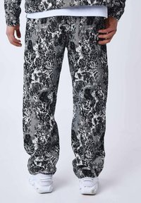 Pantaloni della tuta bianco e nero con una vestibilità ampia, realizzati in tessuto morbido. Accentuati da una vita elasticizzata e orli a mostrine.