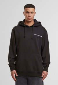 Black hooded sweatshirt made of soft fabric with a kangaroo pocket. Features a white logo on the chest and ribbed cuffs and hem.
