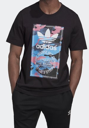 T-shirt en coton noir avec un graphisme camouflage coloré et le logo Adidas. Manches courtes et col rond classique.