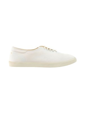 Hvid lavt sneaker i lærred med snørebånd foran og lys beige gummisål, vist fra siden på hvid baggrund.