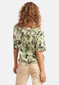 Bluse mit Floral Druck in grünen, schwarzen und beigen Wirbeln. Kurze Ärmel und lockere Passform, aus leichtem Stoff gefertigt. Rückansicht wird gezeigt.