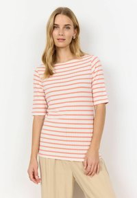 Chemise à rayures à manches courtes en crème et corail, texture côtelée, encolure ronde, conçue avec une coupe décontractée. Associée à un pantalon beige ample.
