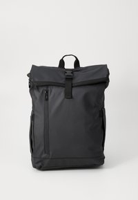 Sac à dos en nylon noir avec un design à rabat, poche zippée à l'avant et poches latérales. Il dispose de bretelles réglables et d'une poignée supérieure.