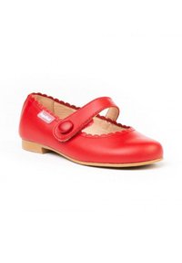 Zapato Mary Jane de cuero rojo con bordes ondulados, una correa ancha asegurada por un botón redondo y una suela de color marrón claro. Textura suave en toda la superficie.