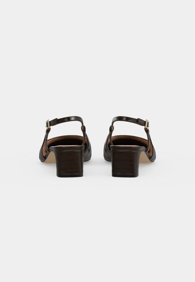 Paire de chaussures en cuir marron foncé à bride arrière, avec des brides de cheville, des boucles dorées et des talons blocs bas, vues de dos.