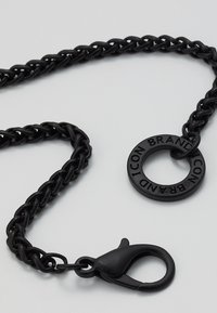 Black chain strap made of thick links with a round rubber logo accent featuring "BRAND ICON." Includes a plastic clip for attachment.