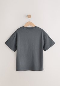 Dark gray short-sleeve cotton t-shirt hanging on a wooden hanger against a white background, shown from the back.