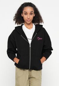 Haut à capuche noir zippé en coton, doté d'une poche avant, de poignets côtelés et d'un logo brodé rose sur le côté gauche.