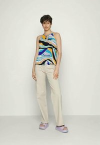 Top tank colorido com padrão abstrato em azul, amarelo e preto. Combinado com calças bege e sandálias plataforma em lavanda.