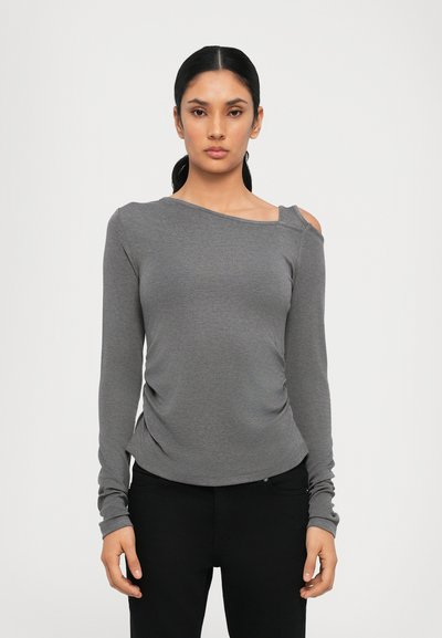 Top gris de manga larga con un escote asimétrico y un lado gather, hecho de tela suave. Combinado con pantalones negros, enfocado en el ajuste y el diseño.