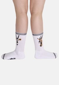 Weiße Baumwollsocken mit schwarzem und beigem Giraffendesign, mit schwarzen gestreiften, gerippten Bündchen sowie festen Fersen- und Zehenbereichen.