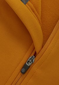 Orange hoodie-tyg med slät textur, med en dragkedja med metallisk hårdvara och en svart dragflik, som framhäver en mjuk inners lining.