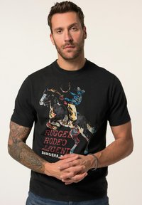 Schwarzes Baumwoll-T-Shirt mit einem bunten Grafikmotiv eines Cowboys auf einem Pferd, mit dem Schriftzug "RUGGED RODEO LEGENDS" in fettem Rot und Gelb.