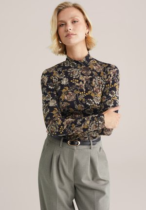 Langemouw shirt met een zwarte achtergrond en een veelkleurig bloemenpatroon; slim fit met een hoge hals, gecombineerd met grijze geplooide broek.