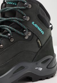 Schwarzer Wanderschuh mit einer strukturierten Lederoberfläche, tealfarbenen Akzenten, Metallösen und einer gepolsterten Zwischensohle für Unterstützung und Langlebigkeit.