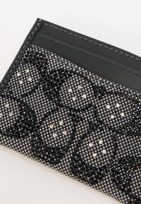 Μαύρος κάτοχος καρτών με υφασμάτινο μαύρο πλέγμα και διαφανή στρας σε λουλουδάτο σχέδιο. Ομαλή δερμάτινη πλάτη και ραφές λεπτομερειών.