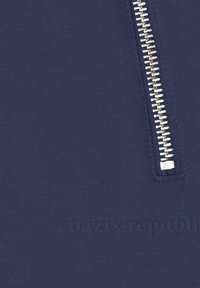 Marineblaues Sweatshirt mit einem silbernen Reißverschluss auf der linken Seite und geprägtem Text "bazix republic" auf dem Stoff. Glatte Textur.