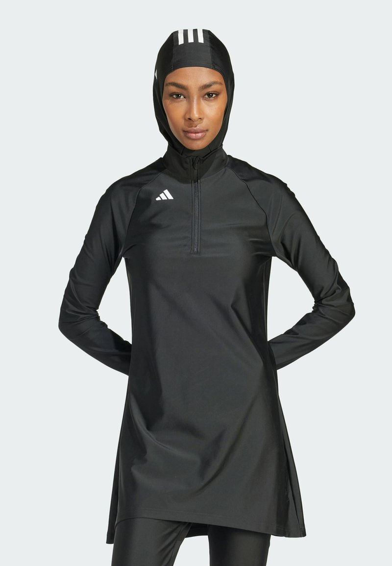 Robe de sport noire avec un col montant, des manches longues et une fermeture éclair. Présente des rayures blanches sur la capuche et le logo Adidas sur la poitrine.