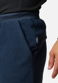 Marine fleece joggers met elastische tailleband, gestructureerde oppervlakte, zijzak en merklabel aan de linkerzijde.