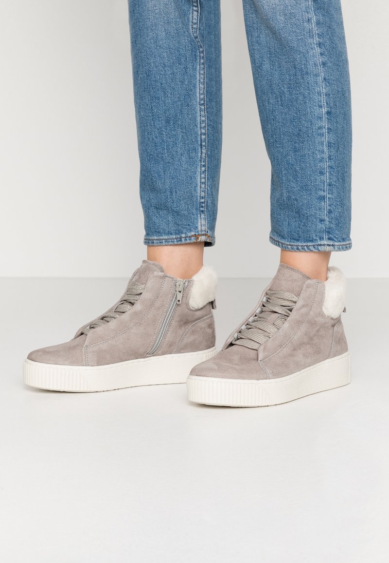 Baskets montantes en daim gris avec semelles en caoutchouc blanches, design à lacets, fermetures éclair latérales et accents en fourrure douce à l'arrière.