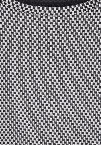 Strickstoff mit einem schwarz-weißen Schachbrettmuster, glatter Textur, runder Ausschnitt und kontrastierenden Farbbanden.