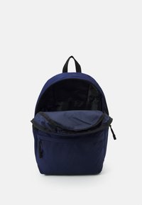 Zaino blu navy con un compartimento principale con zip, una tasca frontale e una maniglia in tessuto. Interno rivestito in materiale nero.