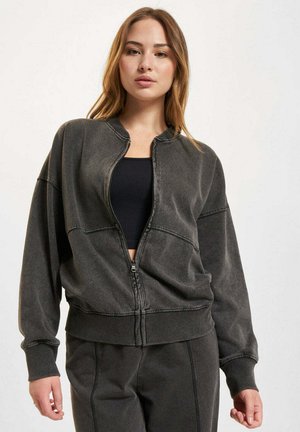 Giacca bomber grigia con zip, dal taglio morbido, con polsini a coste e colletto tondo. Tessuto morbido e testurizzato con cuciture a contrasto.