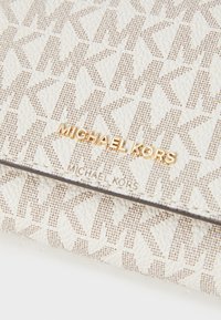 Portafoglio in tela bianca con un motivo monogramma beige. Accent di logo in tono oro. Finitura testurizzata con bordi eleganti.