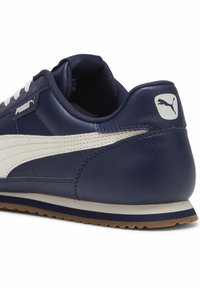 Námořnické tenisky s koženým svrškem, bílým proužkovým detailem a gumovou podrážkou s gumovým podpatkem. Logo na patě a na boku.