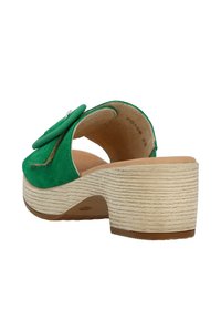 Sandalo mule in suede verde con un elegante dettaglio floreale e tacco in sughero. Suola testurizzata con una forma leggermente curvata.