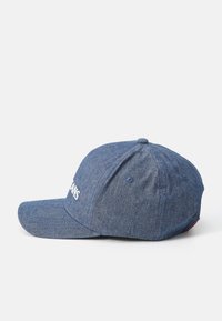 Denim baseball cap with a curved visor, blue fabric, embroidered logo on the front, and a button detail on top. Adjustable strap at the back.