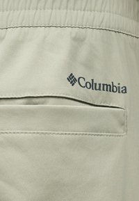 Κοντινό πλάνο σε τσέπη από μπεζ ύφασμα με το λογότυπο Columbia και ραφή ελαστικής μέσης.