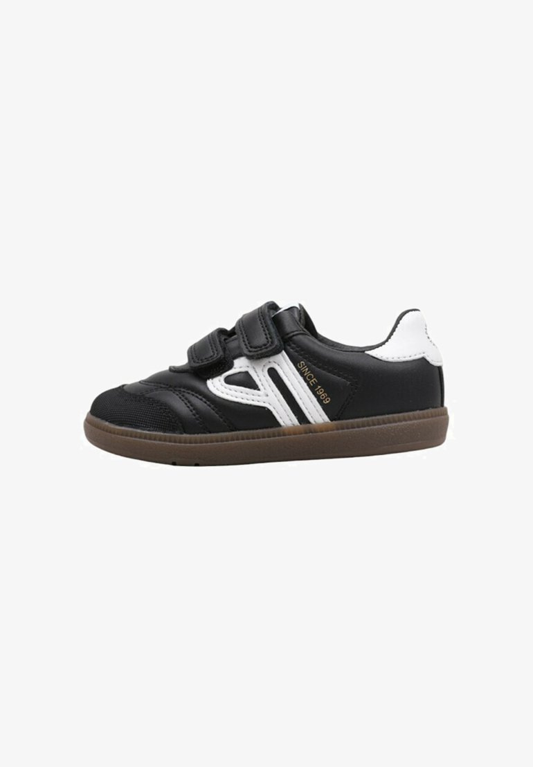 Zapatilla deportiva negra con dos correas de velcro, acentos blancos en los laterales, parte superior negra texturizada y suela de goma marrón. Adecuada para deportes y uso casual.