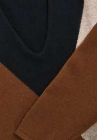 Maglione lavorato a maglia con scollatura a V, in colori a blocchi di navy, beige chiaro e marrone. Texture morbida con dettagli di cucitura zigzag in contrasto.