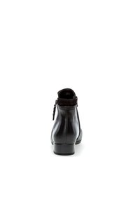 Botín negro de cuero con un acabado suave, puntera redondeada, tacón bajo en bloque y cremallera trasera, que presenta un sutil acento similar al ante en la parte superior.