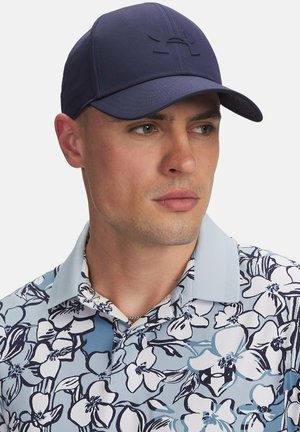 Merin navy-baseball lippu, jossa on sileä pinta ja brodeerattu logo, yhdistettynä vaaleansiniseen kukkakuosisessa paitaan, jossa on valkoisia ja navy-värisiä korostuksia.