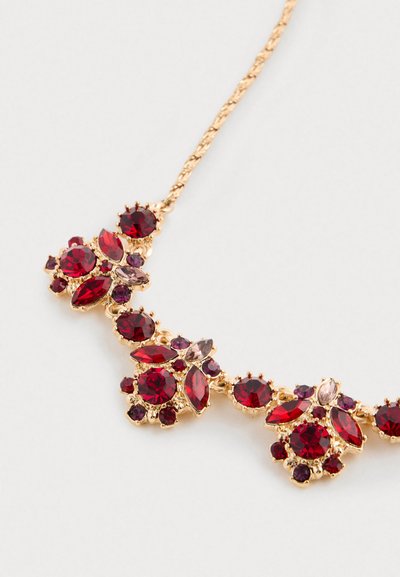 Collana d'oro con gruppi di gemme rosse e viola a tagli rotondi e marquise su uno sfondo bianco.